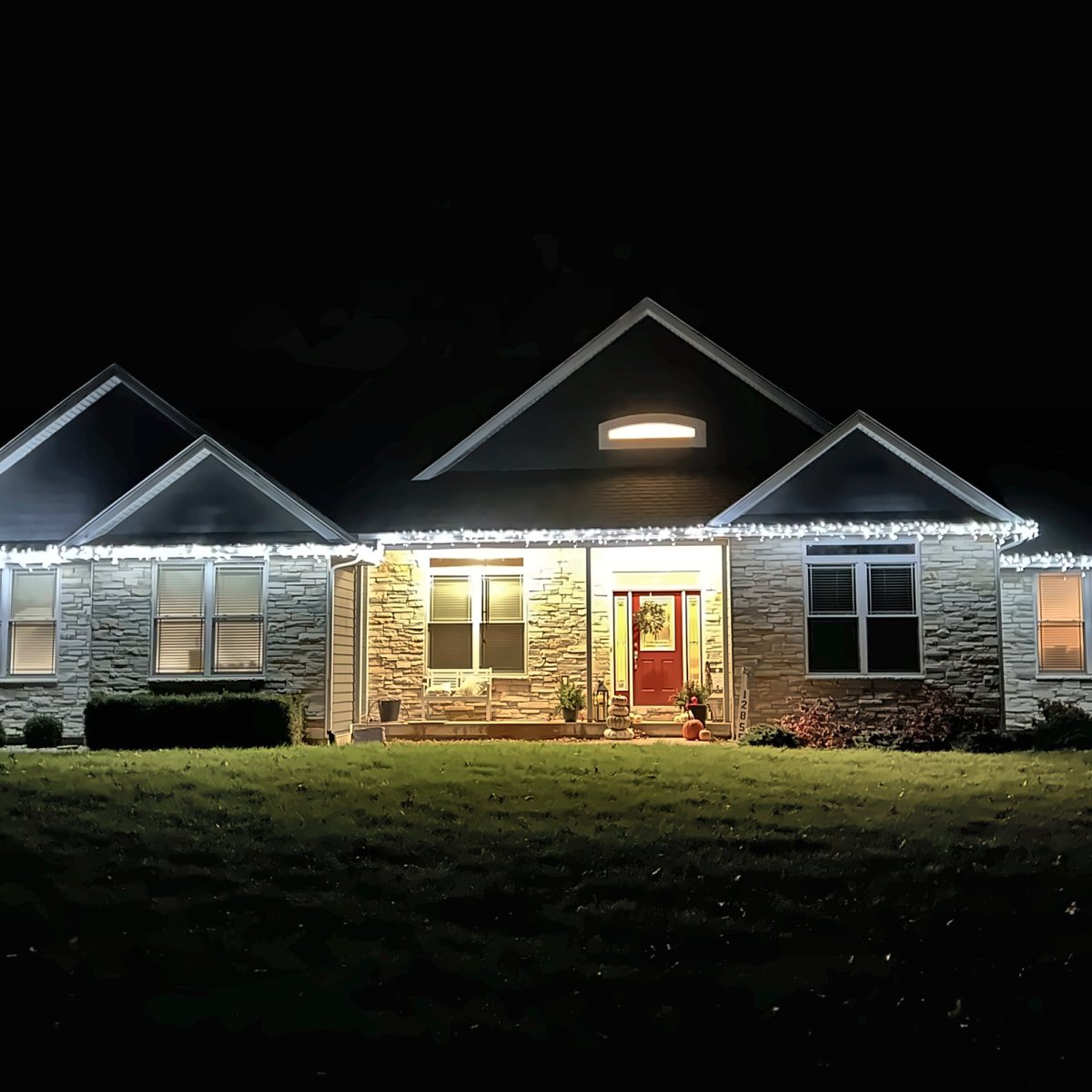 Stone ranch home with cool white icicle lights along every roofline
